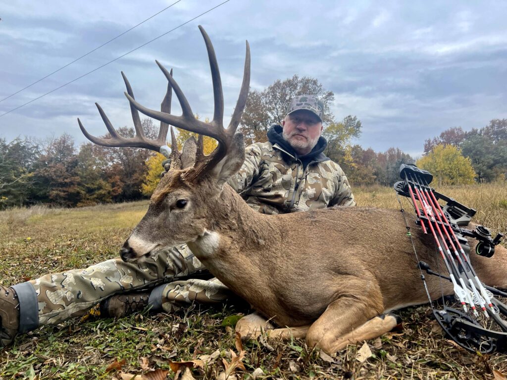 Man posing with deer trophy wearing camouflage.