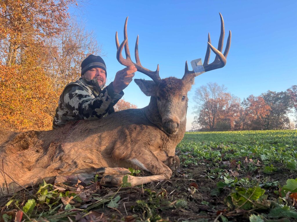 Man posing with deer trophy after successful hunt.