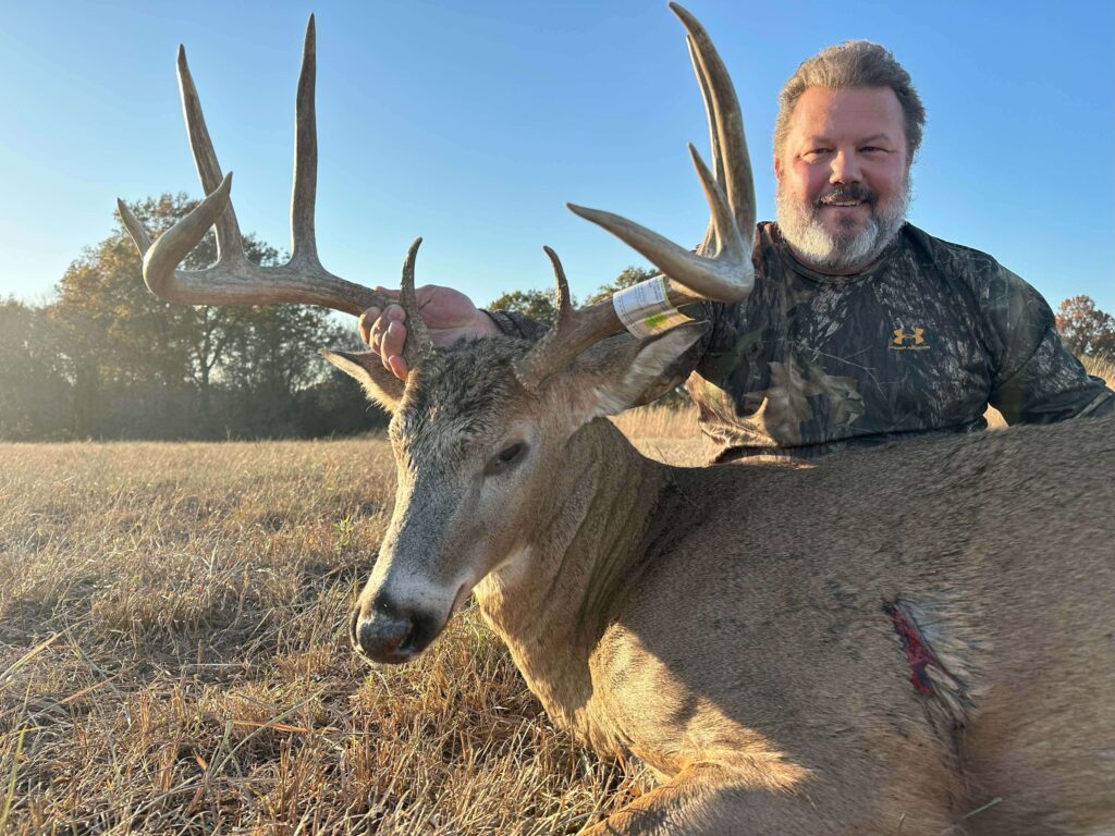 Man posing with deer trophy after successful hunt.