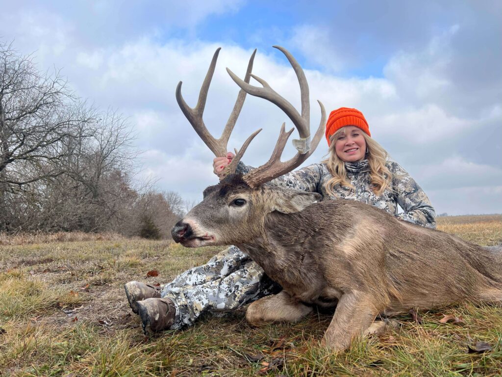 Woman posing with deer trophy after successful hunt.