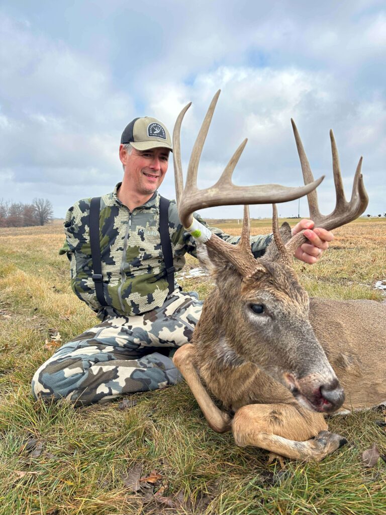 Man posing with deer trophy after successful hunt.