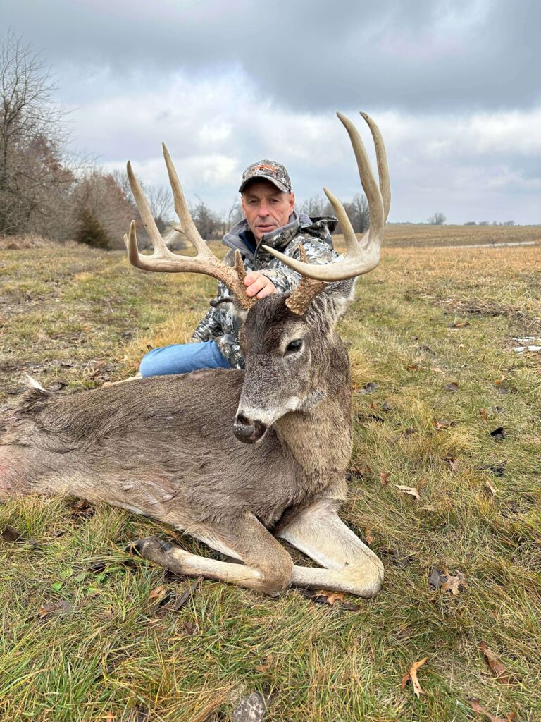 Man posing with deer trophy after successful hunt.