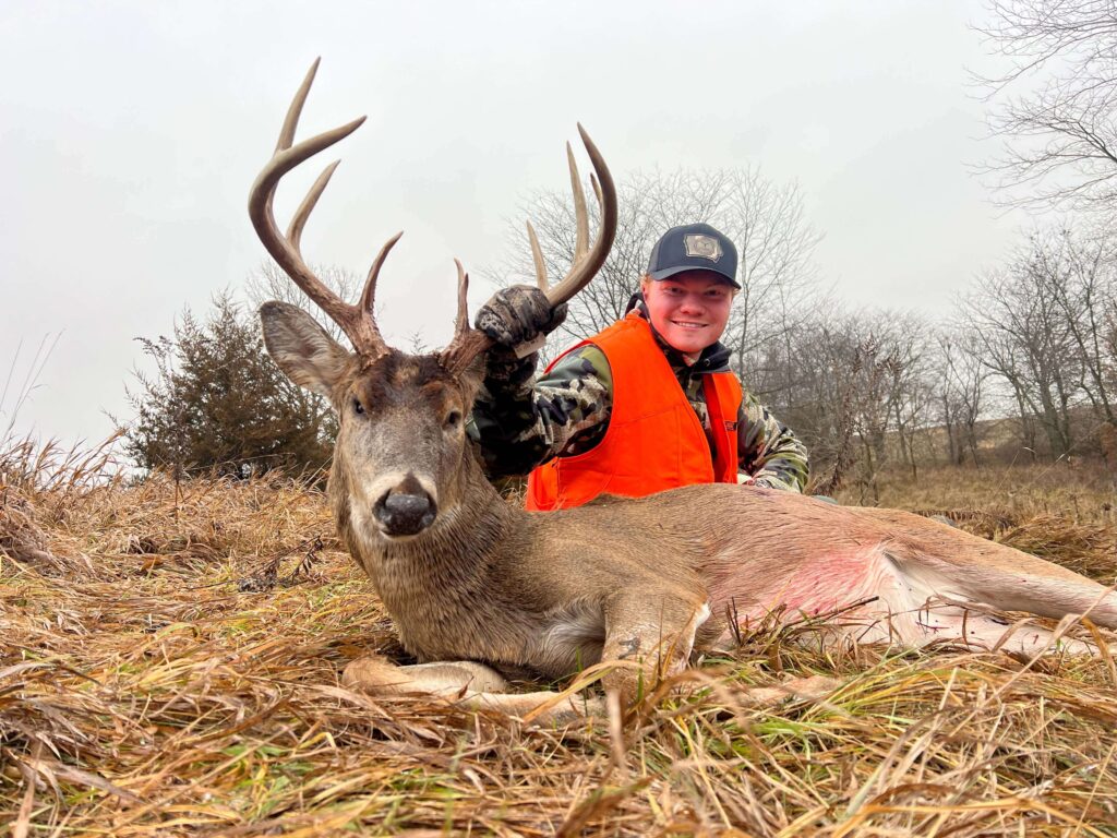 Man posing with deer trophy after successful hunt.