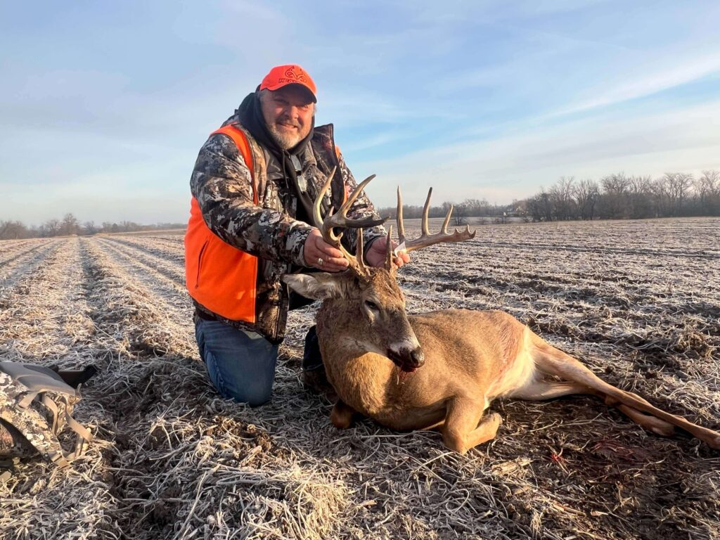 Man posing with deer trophy after successful hunt.