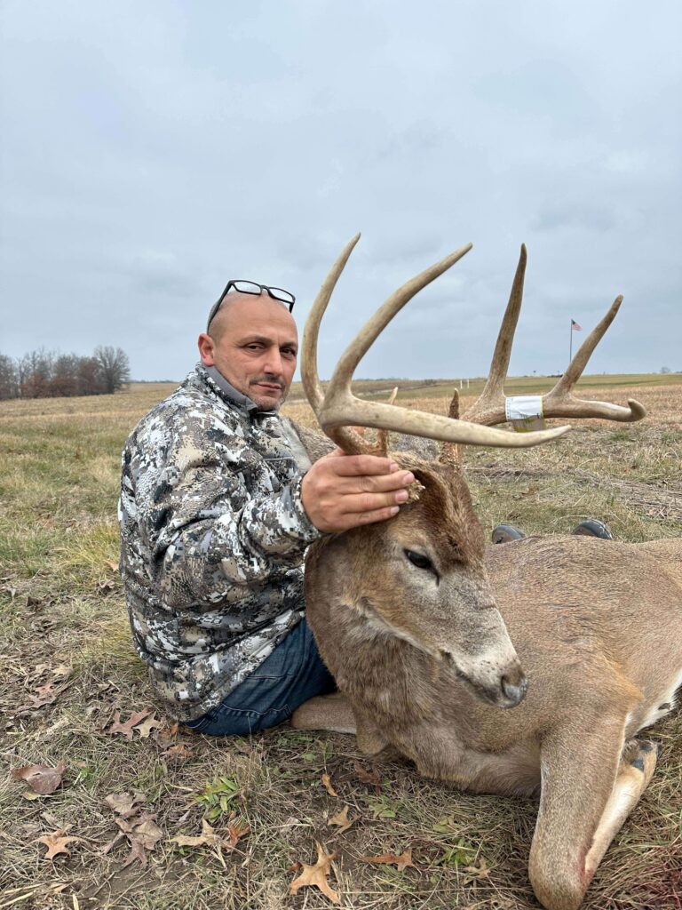 Man posing with deer trophy after successful hunt.