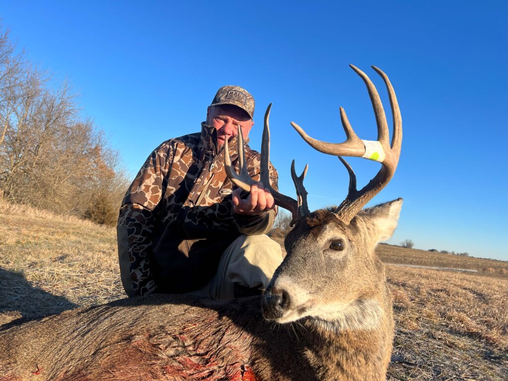 Man posing with deer trophy after successful hunt.