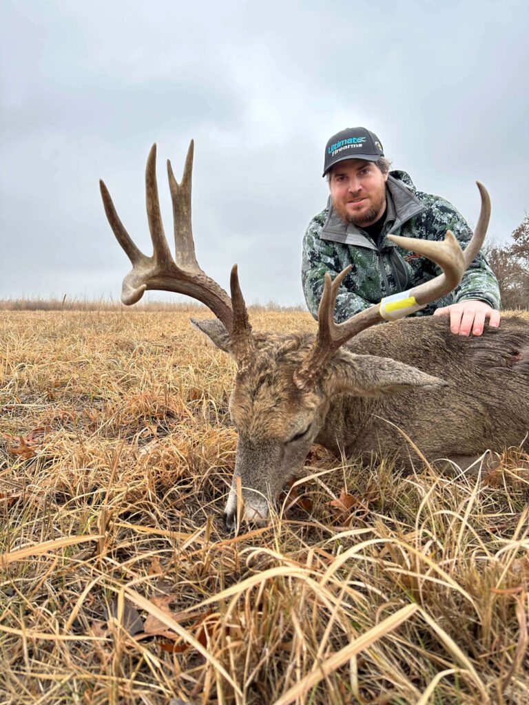 Man posing with deer trophy after successful hunt.