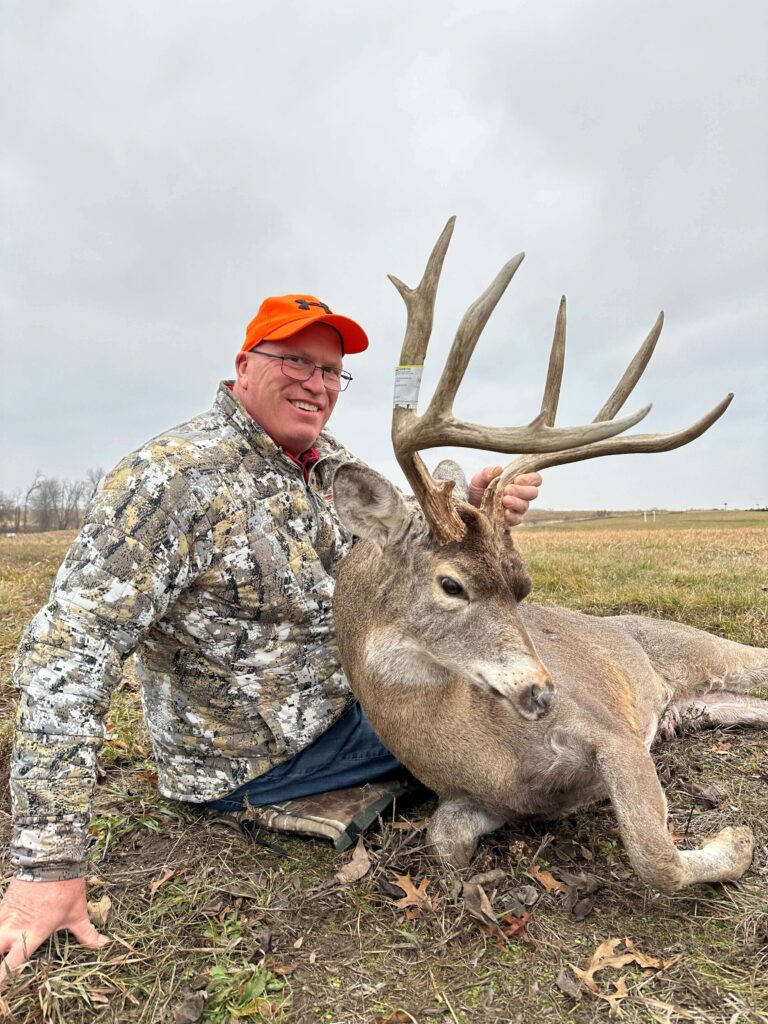 Man posing with deer trophy after successful hunt.