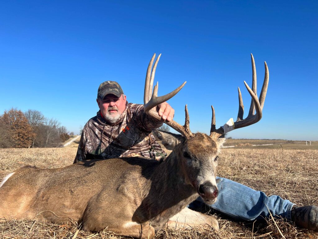 Man posing with deer trophy after successful hunt.