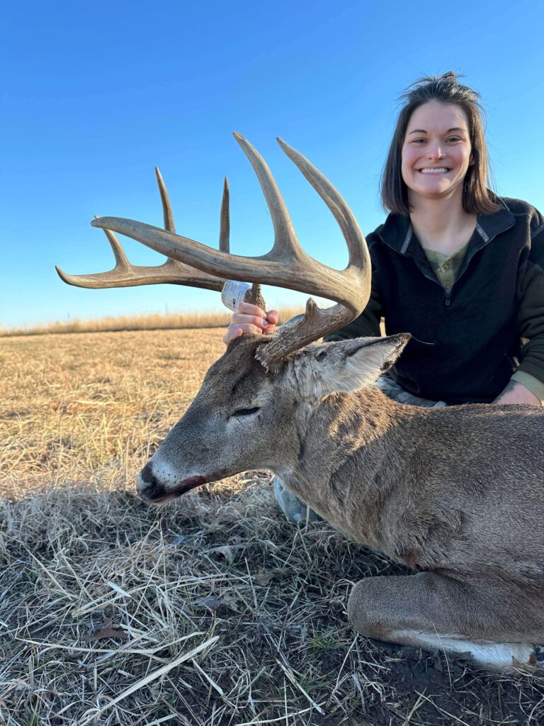 Woman posing with deer smiling.