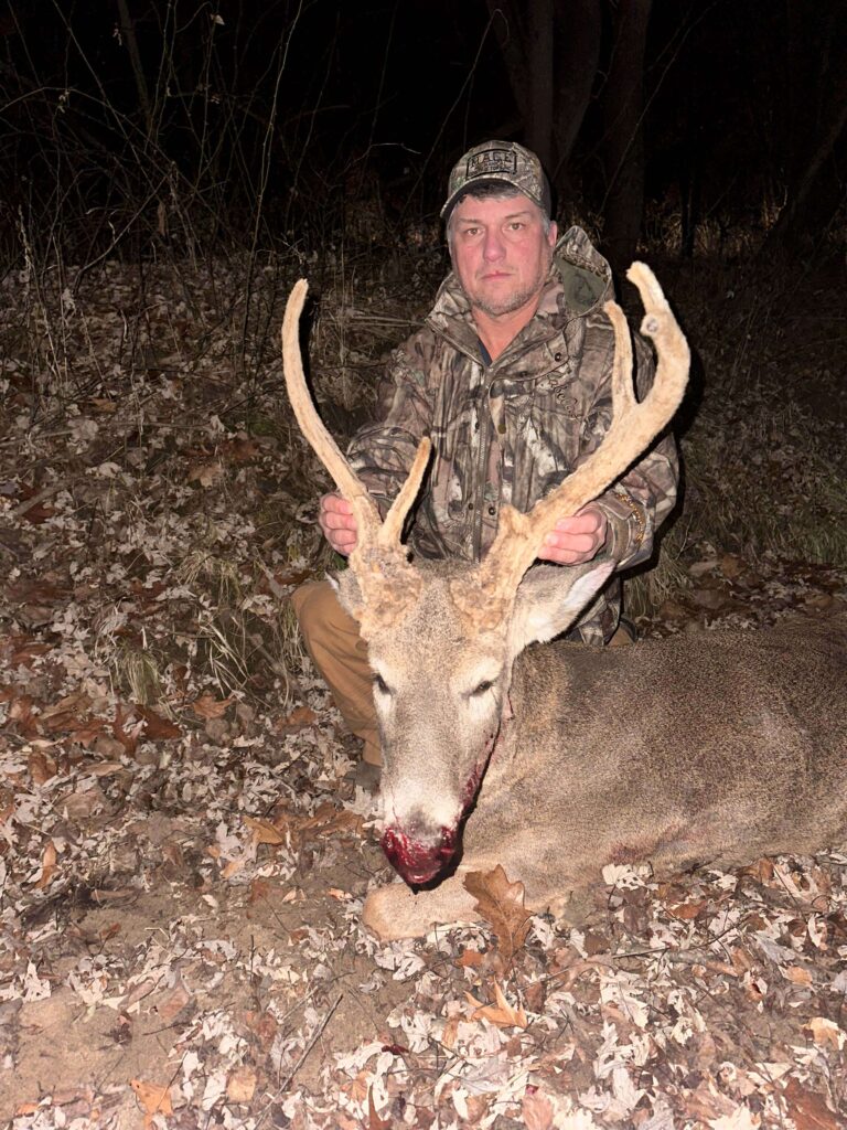 Man posing with deer, wearing hat.